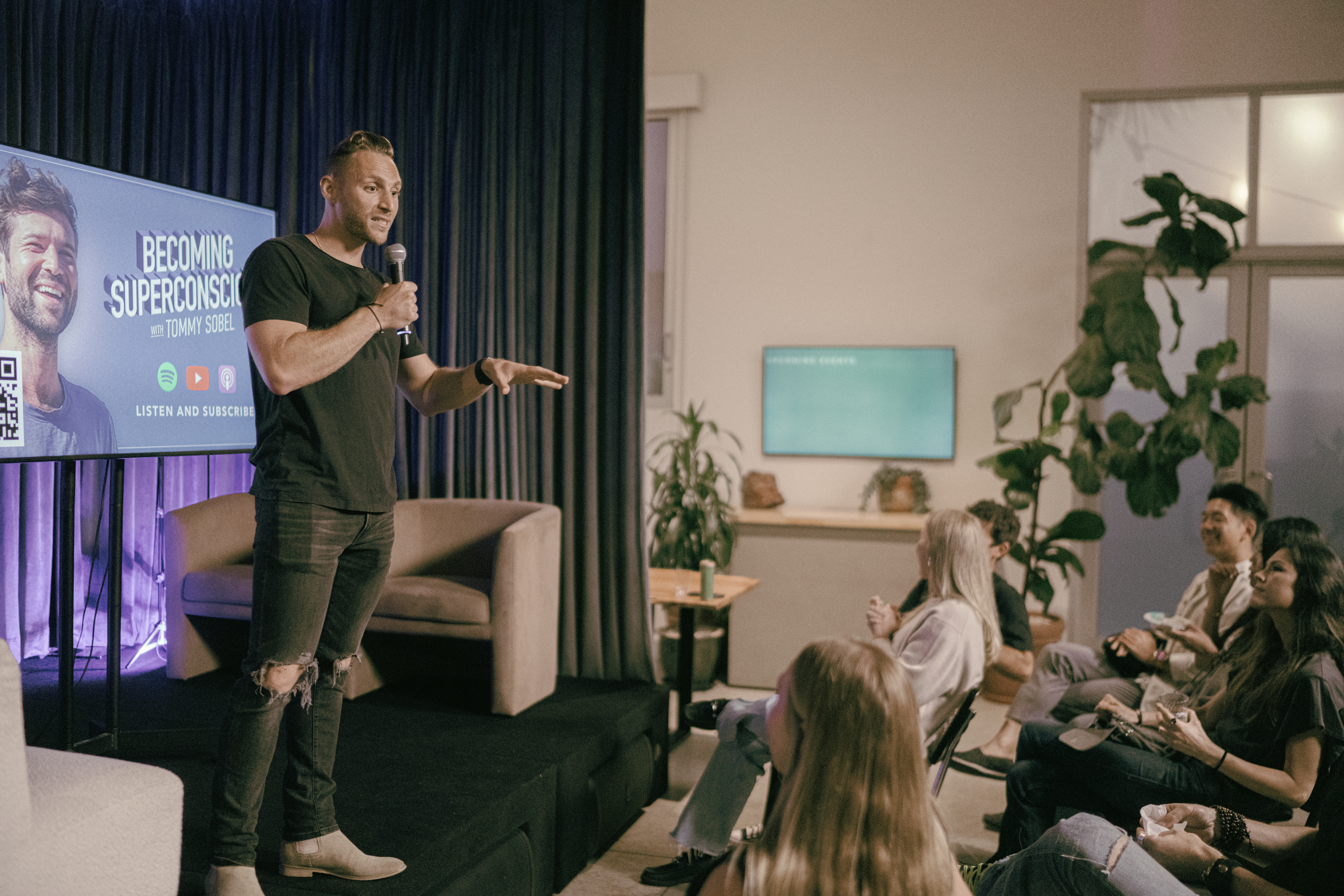 Energy Steve speaking on stage, mic in hand, audience engaged